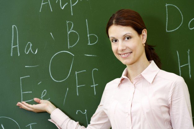 smiling-teacher-with-blackboard-background_1098-866