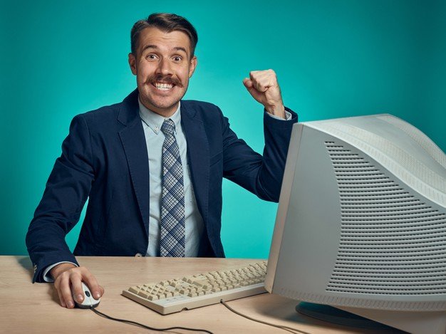 business-man-celebrating-with-his-arm-up-sitting-desk-front-computer_155003-30049
